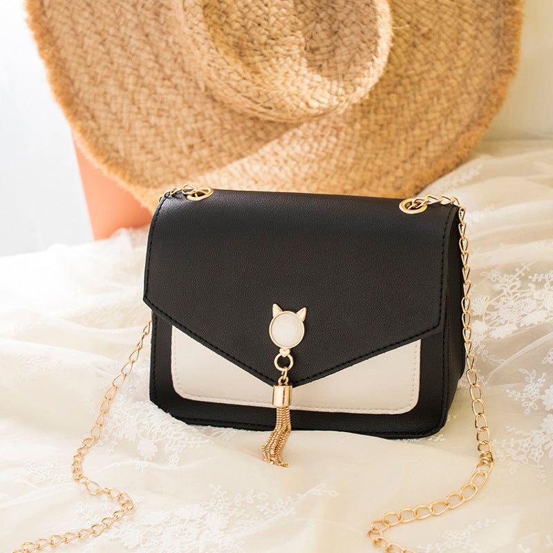 Black and white small square crossbody bag with gold cat clasp and chain strap tassel