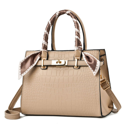 Beige croc-textured tote bag with brown patterned scarf handles and shoulder strap