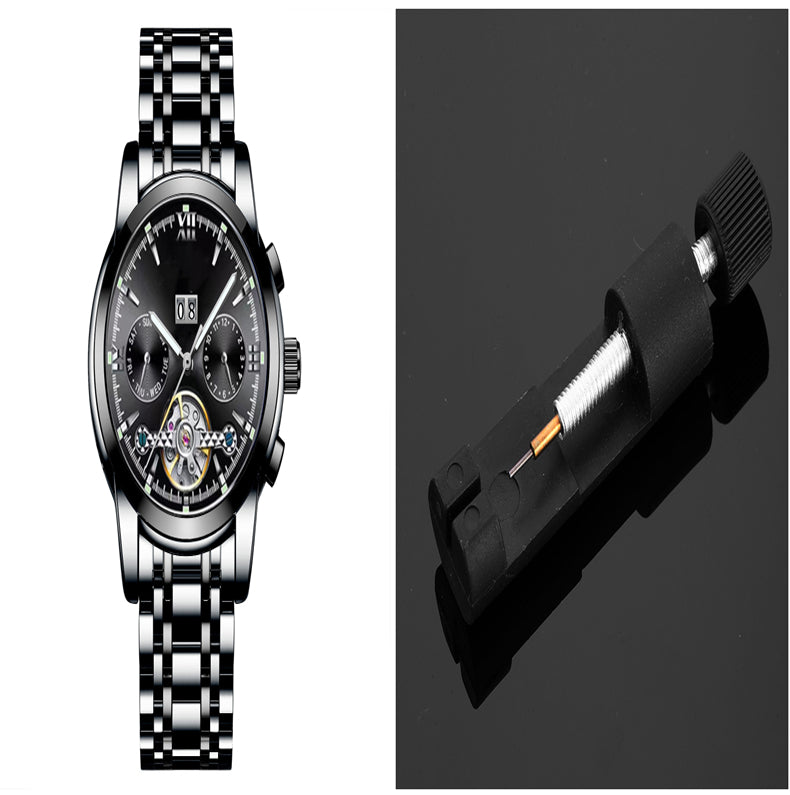 Silver wristwatch with black face and a black tool on a reflective surface