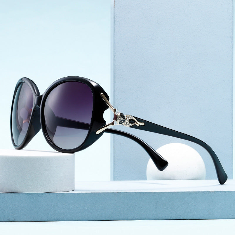 Black sunglasses with a decorative arm on a light blue background
