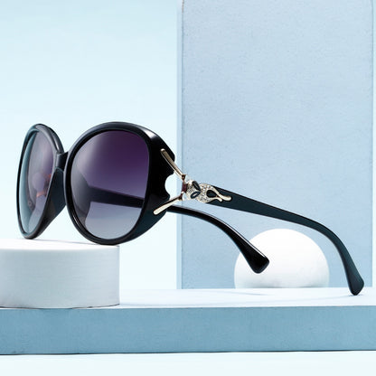 Black sunglasses with a decorative arm on a light blue background