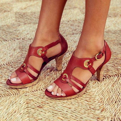 Red high-heeled sandals with gold buckles on a woven surface