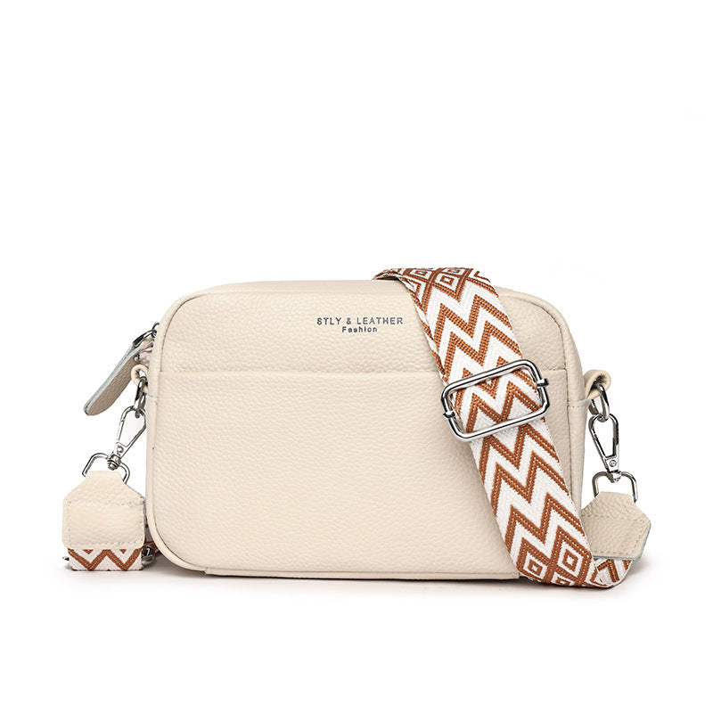 Beige leather-look crossbody bag with zip top and patterned adjustable shoulder strap