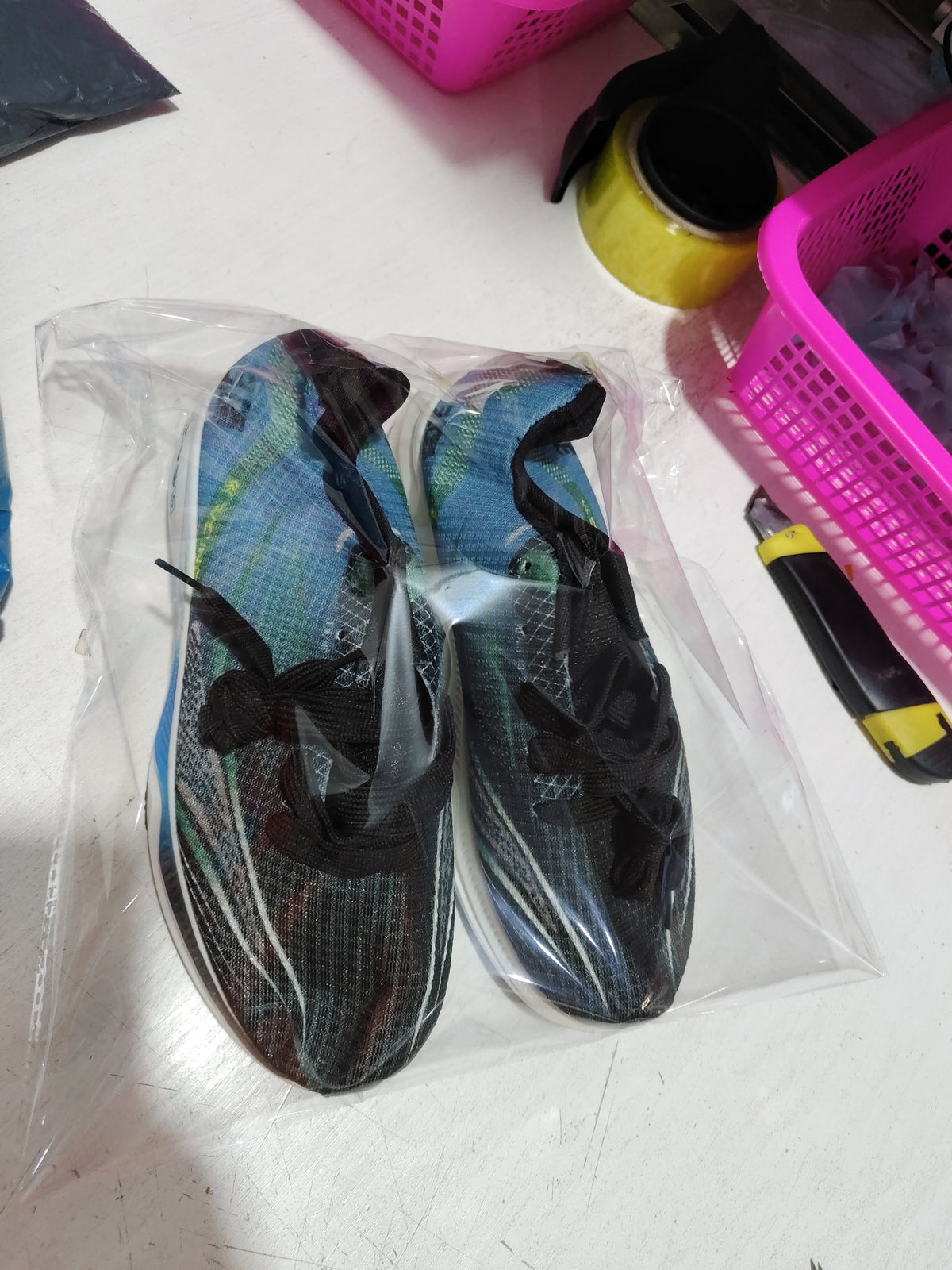 Packaged mesh sneakers in blue and dark tones inside clear plastic bag