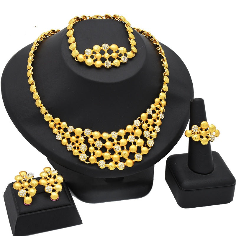 Gold necklace, bracelet, ring, and earrings set on a black stand