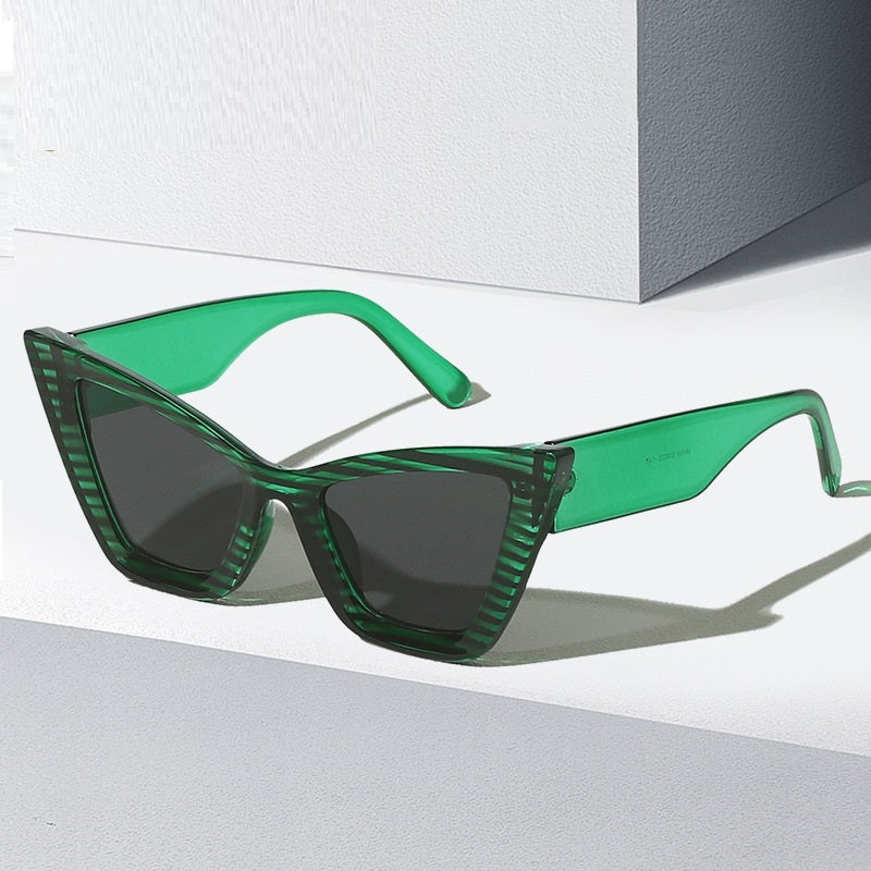 Green cat-eye sunglasses with dark tinted lenses and slim angular frame