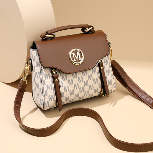 Designer handbag with brown leather top and beige body featuring a logo on a beige background