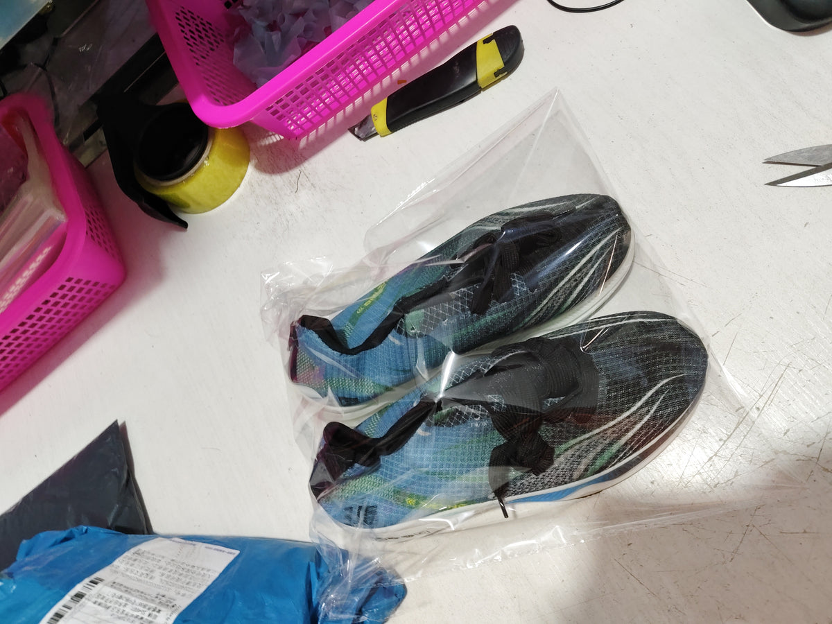 Packaged mesh sneakers in blue and dark colors inside clear plastic bag