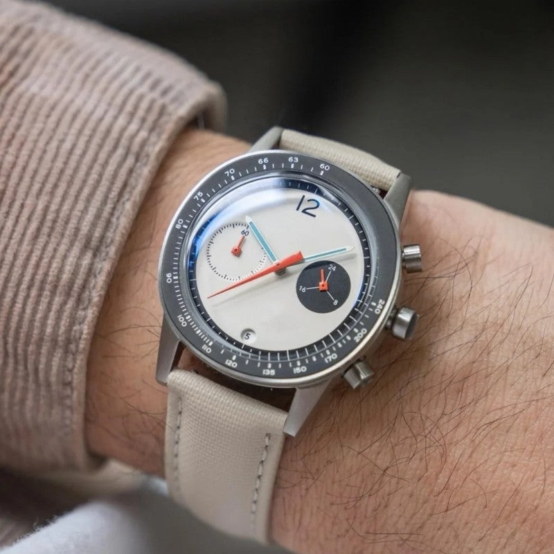 Quartz wristwatch on beige strap with white dial, red accents, and chronograph subdials