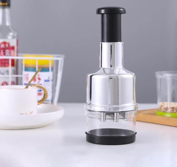 Manual press vegetable cutter with a chrome body, clear collection cup, and black plunger