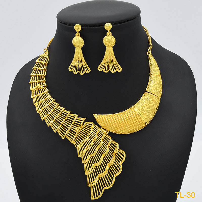 Gold necklace and earrings set on a black mannequin with a light gray background