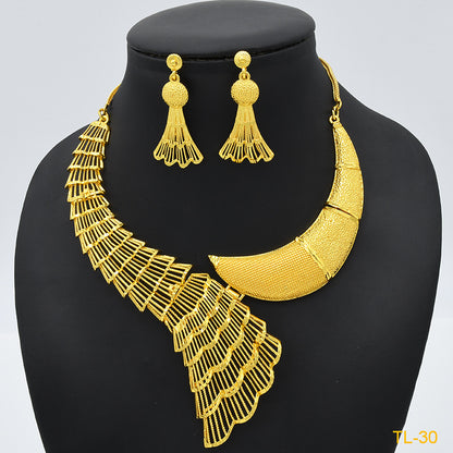 Gold necklace and earrings set on a black mannequin with a light gray background