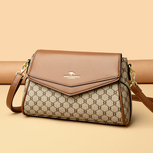 Designer handbag with brown leather flap and patterned body on a beige background