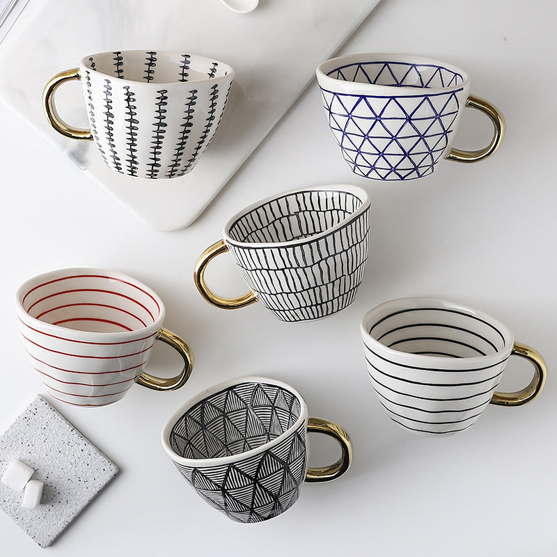 Ceramic mug set with geometric blue and black patterns, gold handles