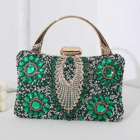 Elegant handbag with green gemstones and gold accents on a white background