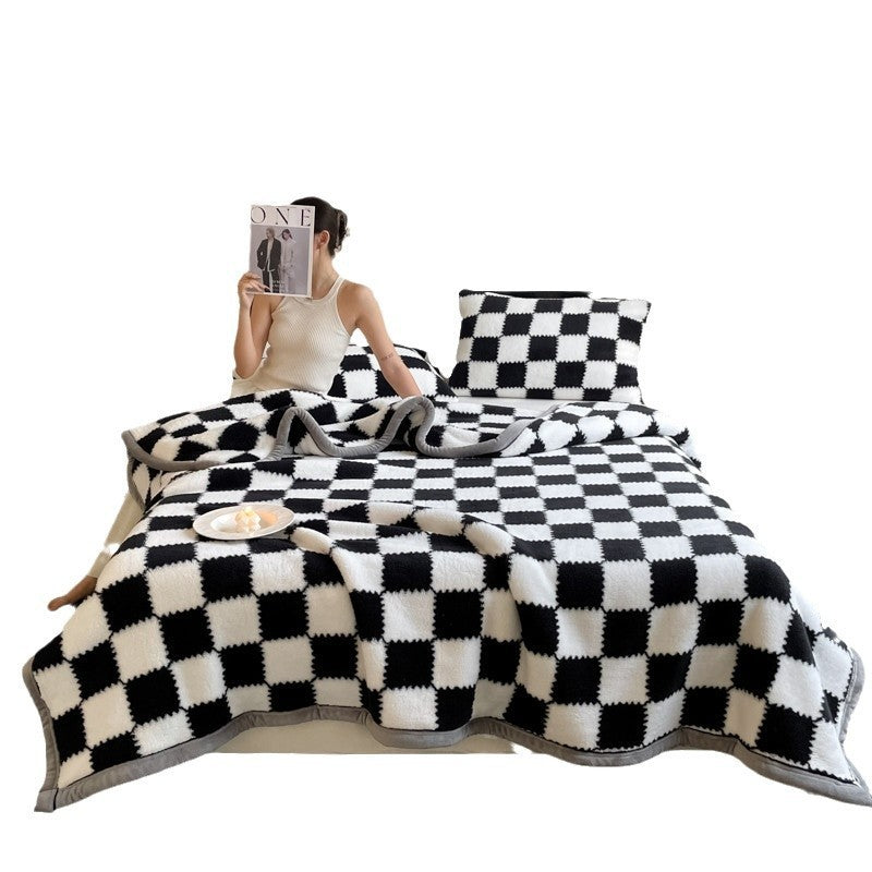 Black and white check plaid blanket with matching pillow, draped on a bed