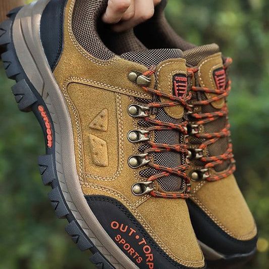 Brown outdoor shoes with orange accents and 'Outdoors' branding on a blurred green background