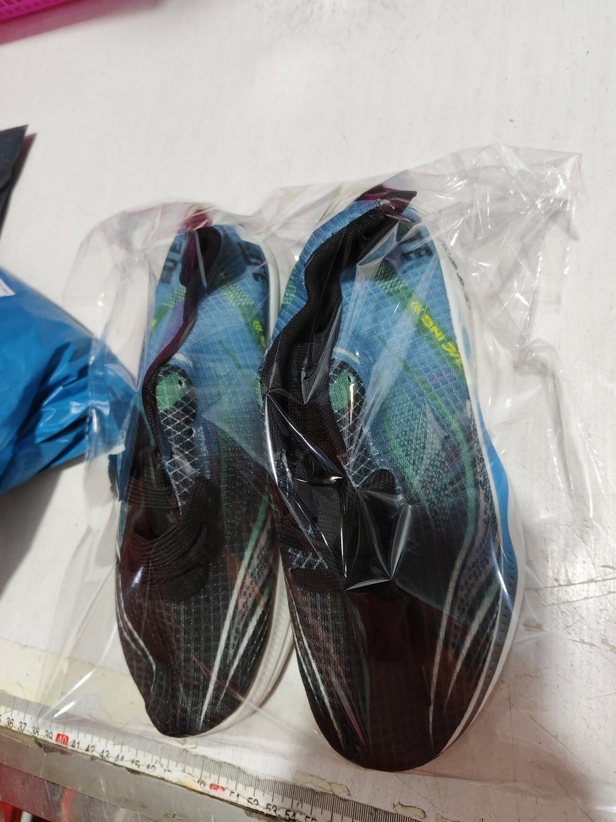 Pair of packaged mesh sneakers in dark colors inside clear plastic bags