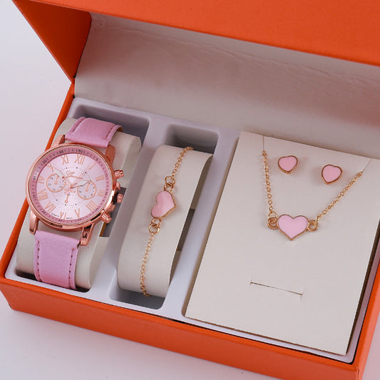 Pink watch, bracelet, and heart-shaped jewelry set in an open orange box.