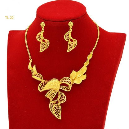 Gold necklace and earrings set on a red velvet stand