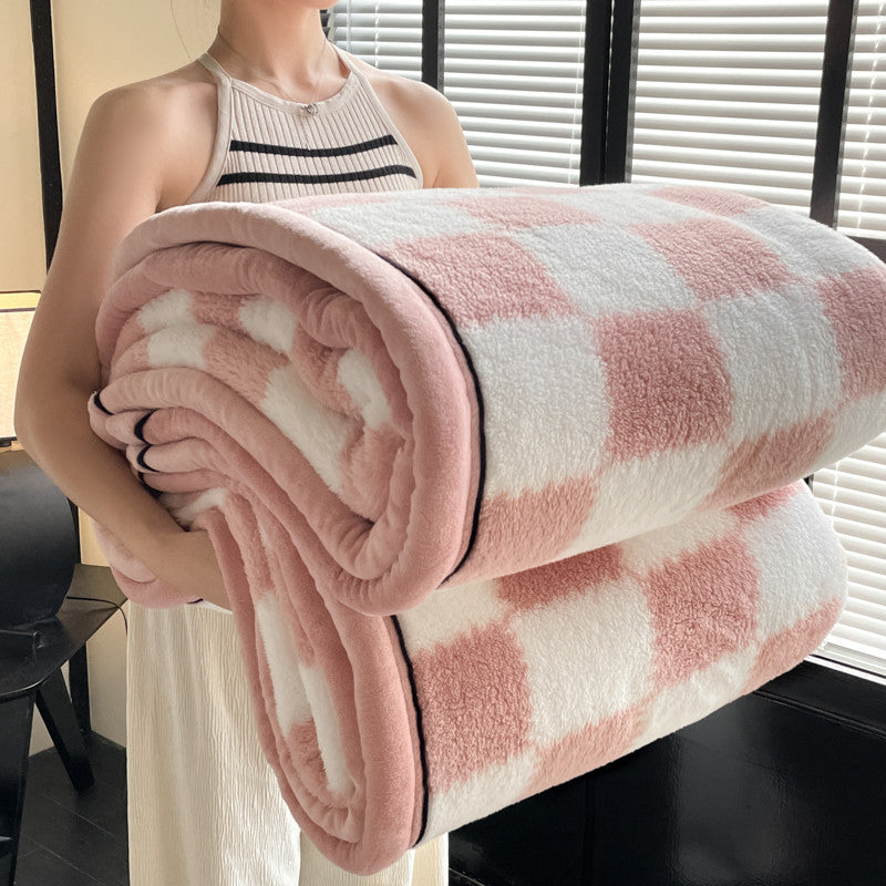 Velvet plaid blanket rolled, pink square blocks on white, plush texture with black trim