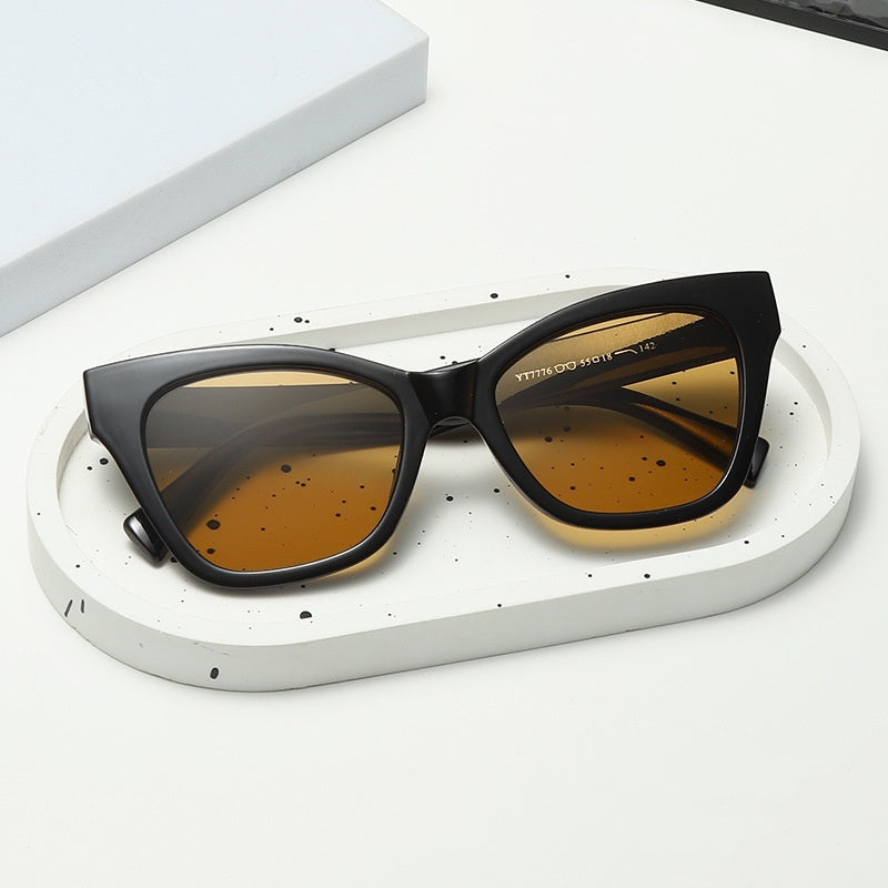 Black cat-eye sunglasses with amber-tinted lenses and curved side arms