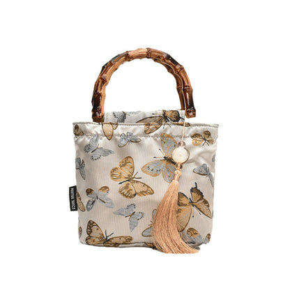 Fabric bag with butterfly pattern and wooden handle on a white background