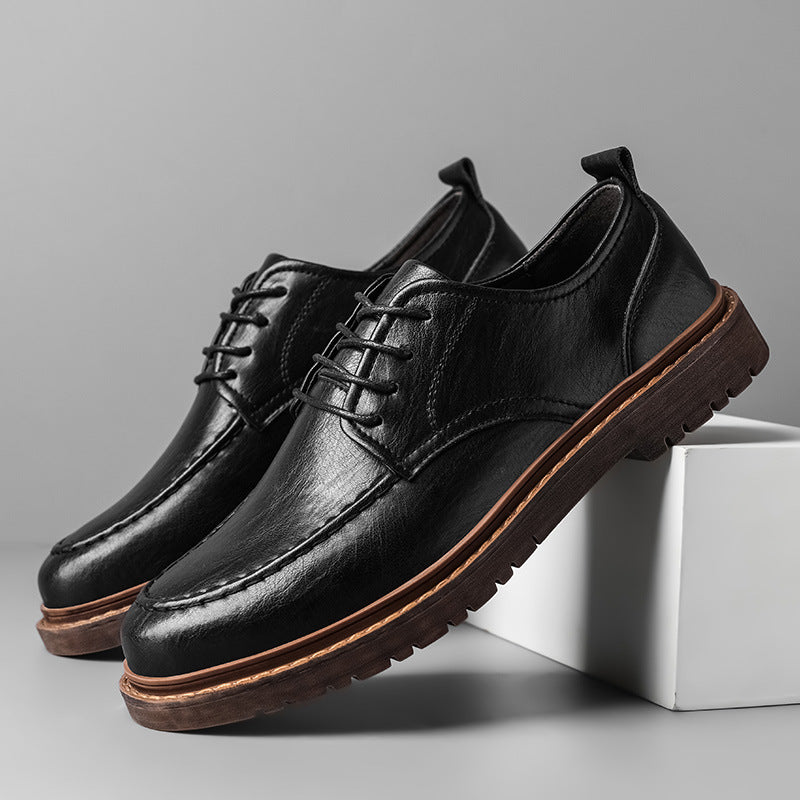 Black leather shoes with brown soles on a gray background