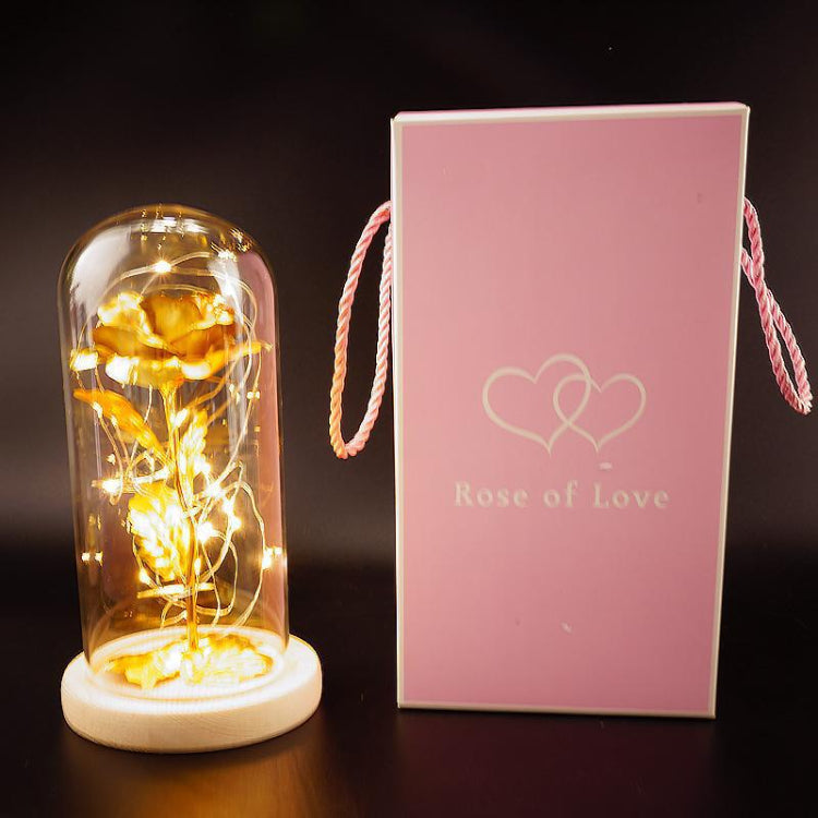 Decorative rose in a glass dome with LED lights next to a pink box labeled 'Rose of Love' on a dark background.