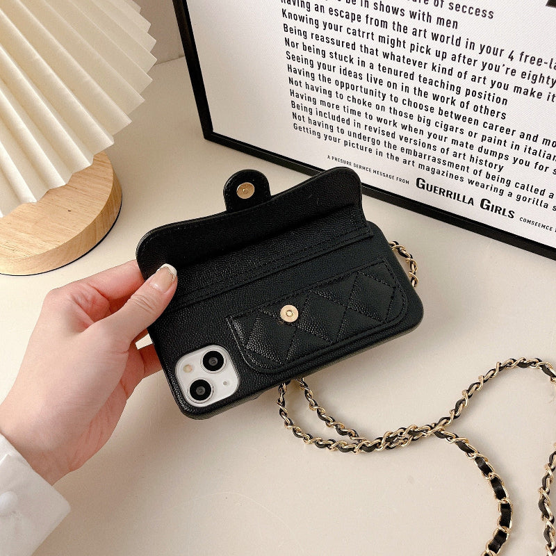 Black quilted phone case with chain held by a hand on a light surface.