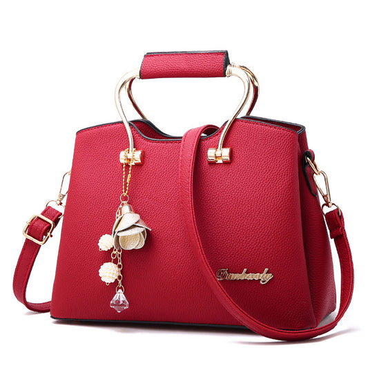 Red handbag with gold accents and a decorative charm on a white background