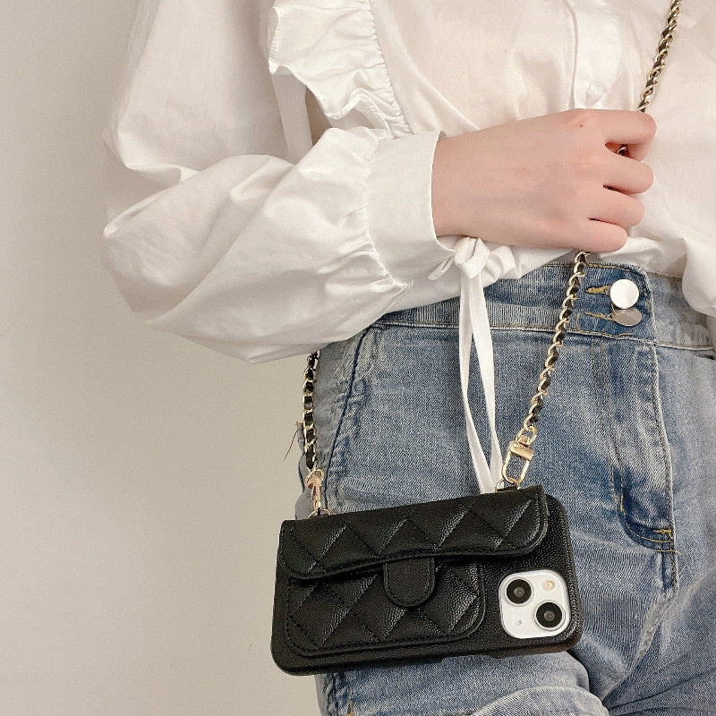 Person holding a black quilted phone case with a chain strap against a neutral background