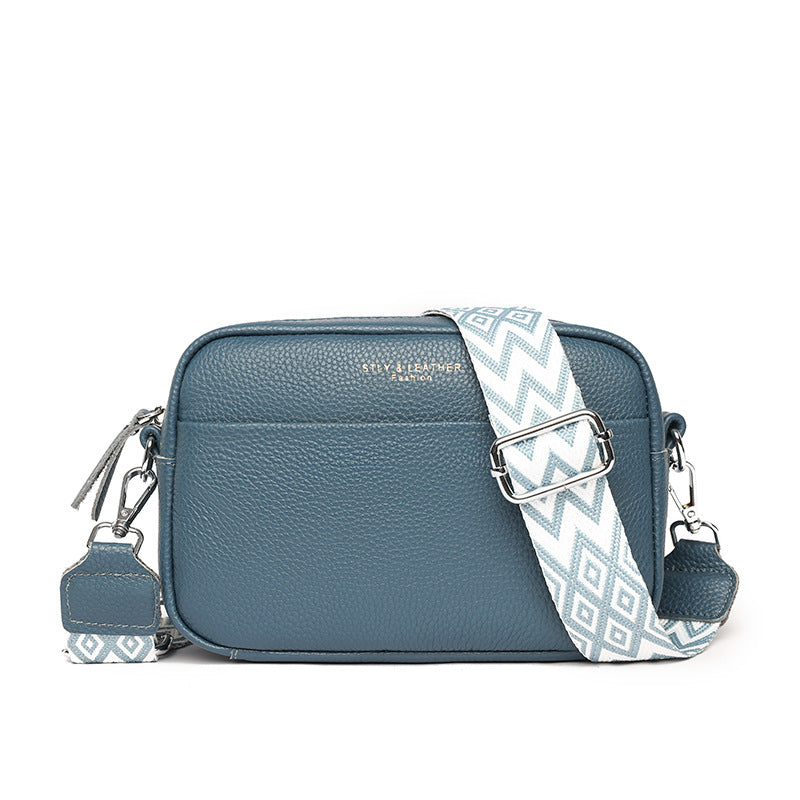 Blue leather-look crossbody bag with zip top and white geometric crossbody strap