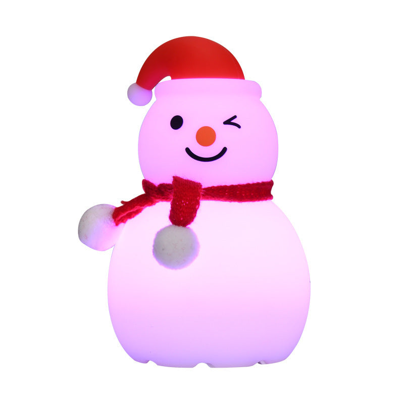 Pink-glowing snowman night light with red hat and red scarf, soft rounded silicone body