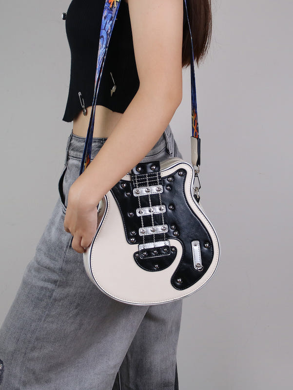 Guitar-shaped crossbody bag with white front, black hardware, and patterned strap