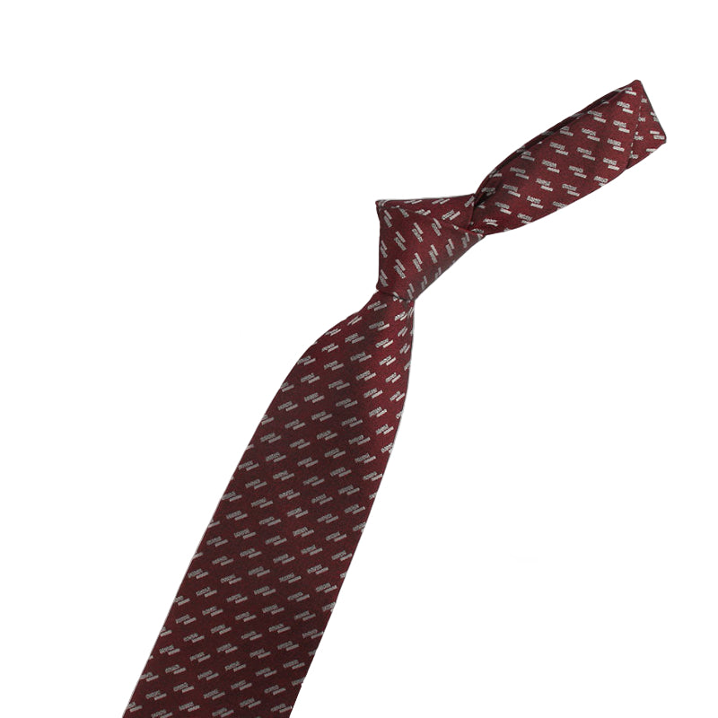 Maroon tie with pattern and two decorative pins on a white background