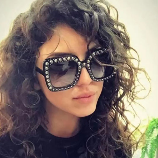 Person wearing large, ornate sunglasses with a blurred background