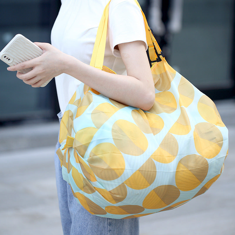Person holding a yellow and blue patterned bag outdoors