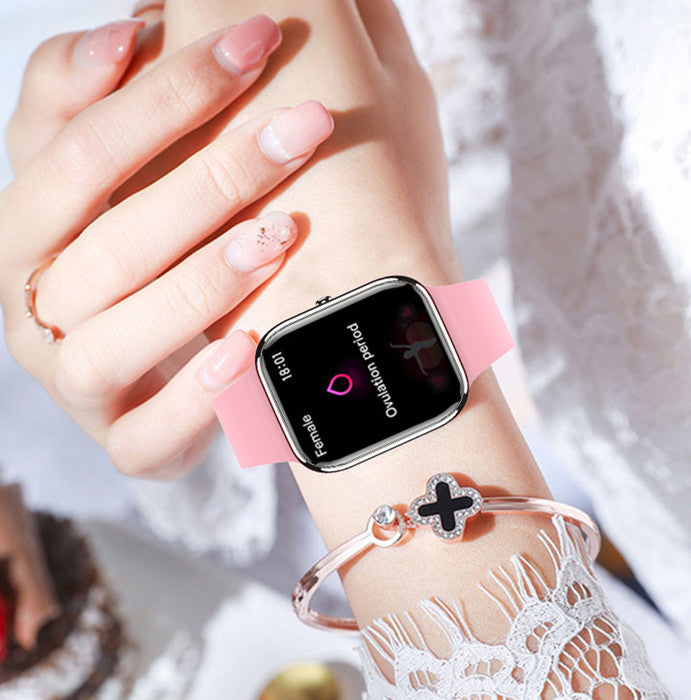 Smartwatch with a pink band on a wrist, with a blurred background