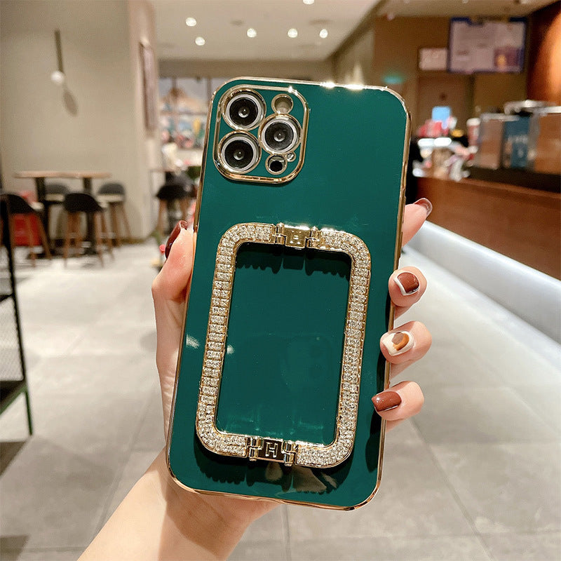 Teal phone case with a decorative ring holder held by a hand in an indoor setting.
