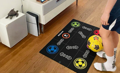 Black training mat with circular soccer markers and arrow patterns; close-up foot