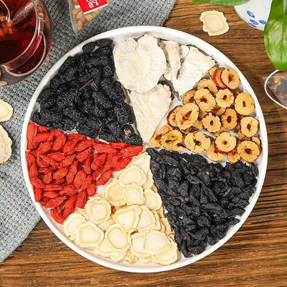 Round tray of dried tea ingredients with red berries, black pieces, and pale slices