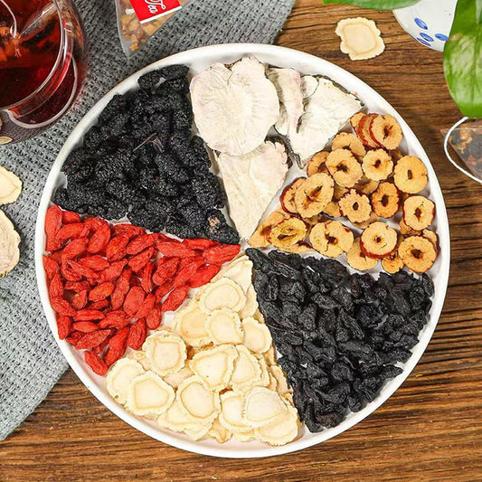 Round tray of dried tea ingredients with red berries, black pieces, and pale slices