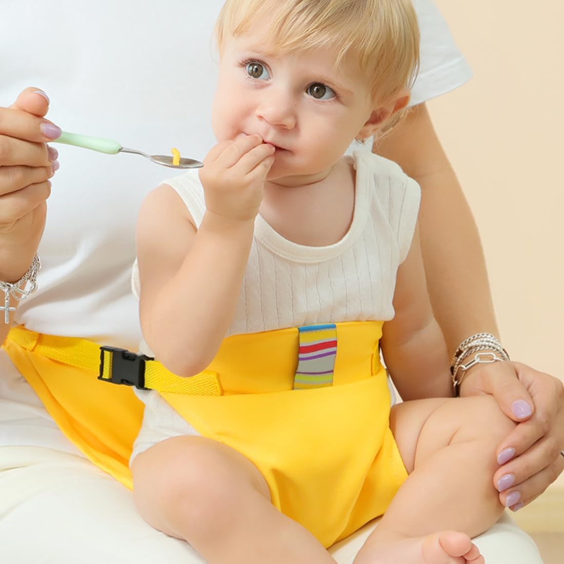 Yellow baby seat belt secured around a child at the waist with adjustable side buckles.