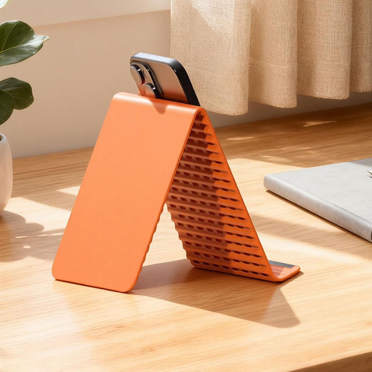 Orange ribbed silicone phone stand supports a phone in portrait orientation.