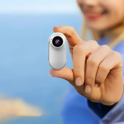 Mini-Motion View white motion camera held between fingers, showing its front lens