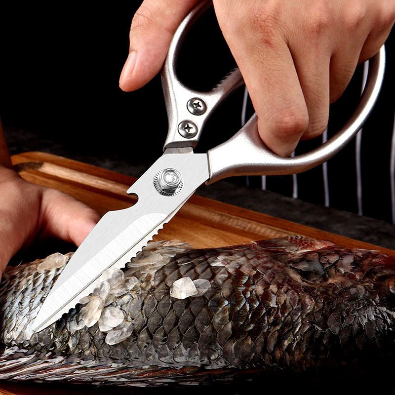 Silver kitchen scissors scraping scales from a fish.