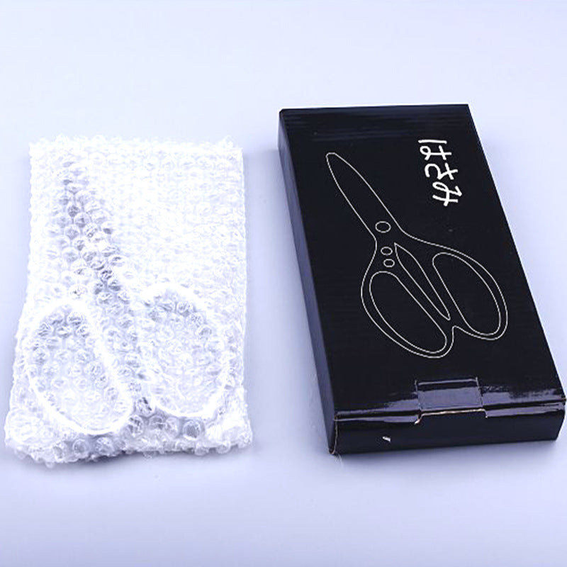 Kitchen scissors in bubble wrap beside a black storage box.