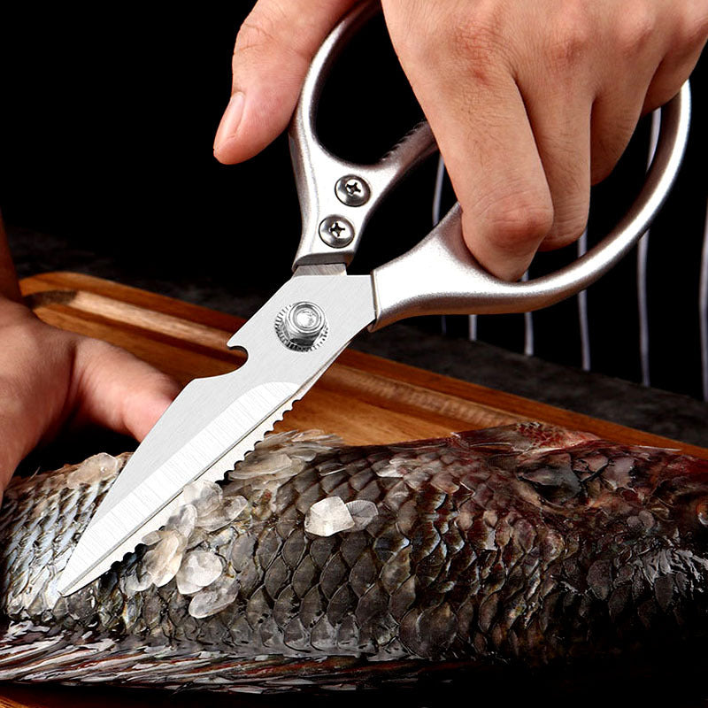 Silver kitchen scissors scraping scales from a fish.