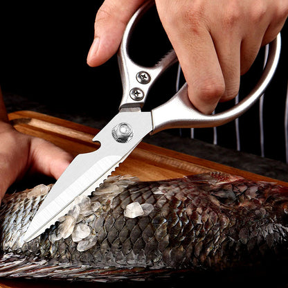 Silver kitchen scissors scraping scales from a fish.
